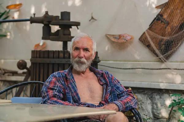 Een Oude Man Een Huisgeruit Shirt Zit Aan Een Tafel — Stockfoto
