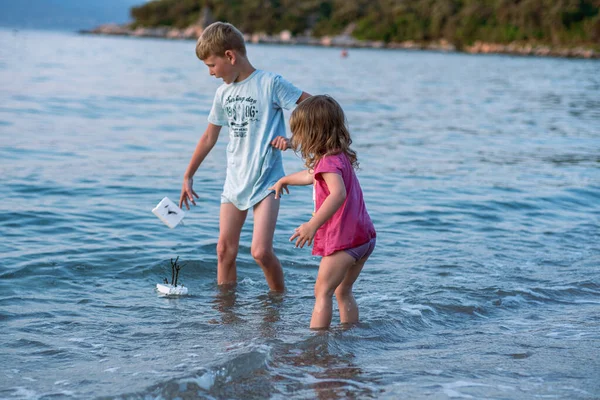 Erkek ve kız kardeş sahilde oynuyorlar. Bir kız ve bir oğlan deniz suyunda ev yapımı teknelerle oynuyorlar. Adriyatik Denizi 'nde çocuklar su sıçratıyor.