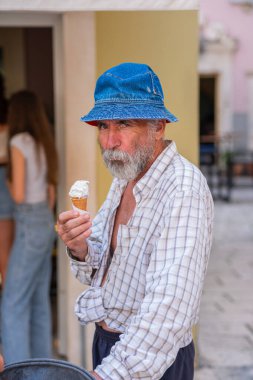 Elinde dondurma olan yakışıklı, yaşlı bir adam. Panama 'da sakallı yaşlı bir adam dondurma tutuyor ve gülümsüyor. Tatil köyünde güneşli bir gün.