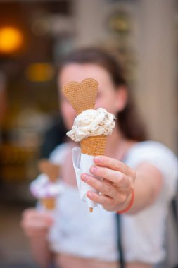 Elinde dondurmayla güzel bir genç kız. Dondurma tutan ve gülümseyen mutlu genç bir kadın. Tatil köyünde güneşli bir gün.