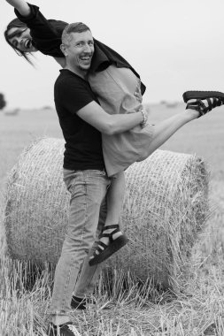 Genç bir çift, kuru saman balyalarının yakınındaki tarlada eğleniyor. Karısıyla bir saman balyasının yanında dans eden bir adam. Siyah ve beyaz resim.