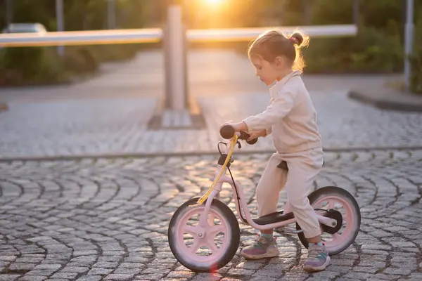 Little Girl Pink Suit Rides Pink Balance Bike Rays Sunset — Stock Photo, Image
