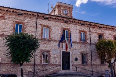 Numana Italy - 19 Sep 2023: Municipality Of Numana. Building of Municipality with clock and flags of: Italy, EU. Numana city. Summer sunny day. clipart