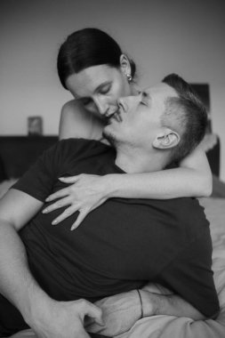 Sensual couple on the bed. A young and attractive caucasian man and woman kiss and hug, loving each other. Beautiful heterosexual couple of lovers.