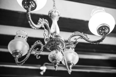Old vintage chandelier shot close up. Black and white photo of a chandelier hanging from the ceiling.