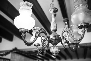 Old vintage chandelier shot close up. Black and white photo of a chandelier hanging from the ceiling.