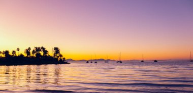 Şafakta deniz limanında. Yükselen güneş tarafından altın rengine boyanmış gökyüzü, denizin sakin dalgalarına yansıyor. Yatlar güzel siluetler içinde gökyüzüne karşı duruyor, şafak vakti banyo yapıyorlar..