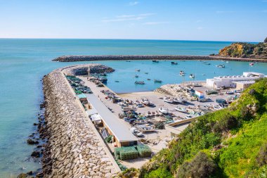 Güneşli bir günde rıhtımda. Karada ve denizde bir sürü tekne, balıkçı ağları ve ekipmanlar. Portekiz 'de okyanus balıkçılığı..