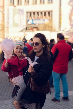 Anne ve kızı Almanya 'da bir sokak festivalinde pamuk şeker yiyorlar. Alman şehrinde bahar tatili.