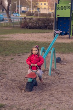 Güzel küçük bir kız parkta tek başına oynuyor. Kız tek başına sıkılmış ve tahterevallide ya da tahterevalliye binecek kimsesi yok ve salıncağın bir tarafında oturuyor..