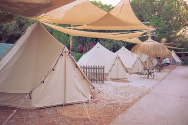Güzel, bakımlı kamp alanı: Fenerli çadırlar, plaj şemsiyeleri ve bahçe mobilyaları. Glamping sahasında modern yeni çadırlar.