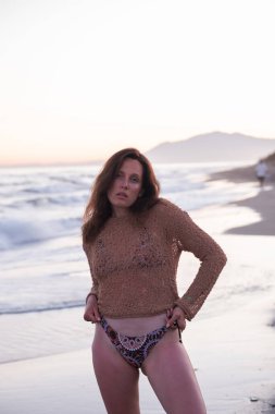 Sıcak bir yaz akşamında sahilin arka planında poz veren güzel bir kız. Arka planda güzel bokeh ve deniz dalgaları.