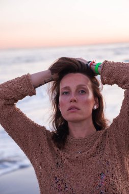 Sıcak bir yaz akşamında sahilin arka planında poz veren güzel bir kız. Arka planda güzel bokeh ve deniz dalgaları.