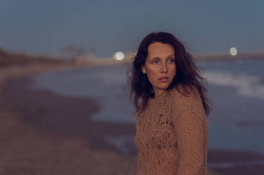 Sıcak bir yaz akşamında sahilin arka planında poz veren güzel bir kız. Arka planda güzel bokeh ve deniz dalgaları.