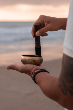 Beyaz yaz kıyafetleri içinde genç yakışıklı adam yaz akşamları sahilde şarkı söyler. Adam yoga yapıyor ve şarkı söyleyen kâse ve deniz dalgalarından gelen sesle meditasyon yapıyor. 4K video.