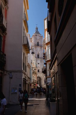 20.10 dolar. 2024 - Malaga, İspanya: Eski kasaba, caddenin karşısındaki büyük güzel katedralin manzarası. Sokakta yürüyen insanlar. Dikey fotoğraf.