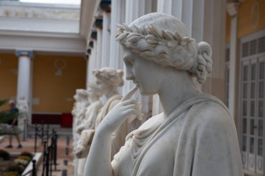 Çelenklerdeki Antik Kadın heykelleri. Beyaz taş heykeller Yunan tarzı sütunlar arasında düzenli bir sıra halinde duruyorlar.