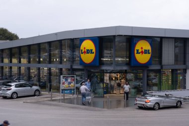 Kerkyra, Yunanistan - 09: 24 2022: Lidl süpermarket, müşteriler mağazaya girip çıkıyor. Otoparkta hareket eden arabalar..