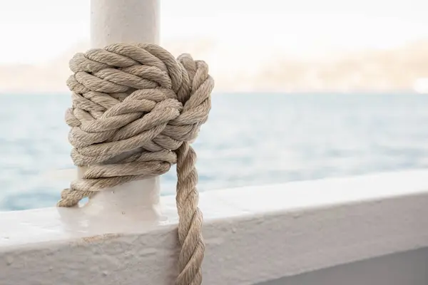 Bir halat, bir deniz gemisinin güvertesinde düğümlenir. Deniz düğümüne yakın çekim. Gemi halatı.