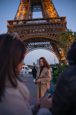 Paris 'teki Eyfel Kulesi' nin arka planında poz veren güzel bir kız. Paris 'te akşam, parıldayan Eyfel Kulesi ve güzel genç bir kadın..
