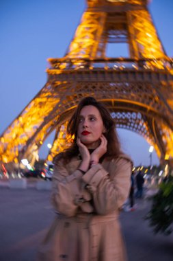 Bulanık kavramsal modern fotoğraf. Paris 'teki Eyfel Kulesi' nin arka planında poz veren güzel bir kız. Paris 'te akşam, parıldayan Eyfel Kulesi ve güzel genç bir kadın..