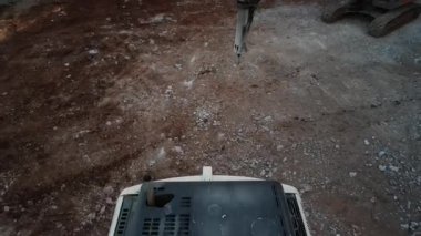 Ağır kayaları ve toprağı kamyona yükleyen bir kazıcının hava görüntüsü. Bir İHA inşaat malzemelerinin üzerinden uçuyor..