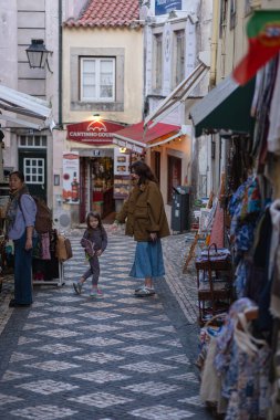 06.02. 2025 - Sintra, Portekiz: Anne ve kızı alışveriş merkezlerinin arasında eski kentin sokaklarında geziniyor. Yerdeki mozaik fayanslar, eski evler ve kapılar, birçok dükkan..