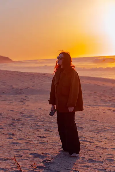 Genç, güzel ve şık giyinmiş bir kız engin bir okyanus sahilinde güzel bir günbatımının ve azgın dalgaların önünde yürüyor. Özgürlük ve hayatın keyfi, seyahat ve rahat yaşam.