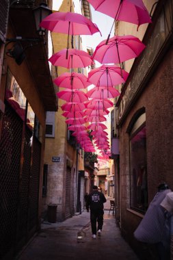 Bir İtalyan şehrinde güzel dar bir cadde. Cadde kırmızı şemsiyelerle süslenmiştir. Gölge ve güzellik yaratmak için birçok şemsiye en üste asılır..