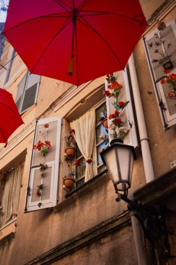 Güzel dekore edilmiş eski bir evin penceresi. Açık panjurlu pencere ve eski bir kasabanın caddesini süsleyen kırmızı şemsiyeler arasında güzel bir dekor..