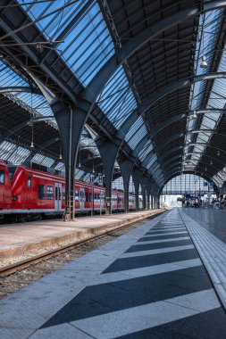 Karlsruhe, Almanya - 20.05.2025: Bir Alman şehrindeki büyük tren istasyonu. Almanya 'da bir tren istasyonunun platformunda kırmızı bir tren duruyor. Metal kolonlar ve çatı kemerleri.