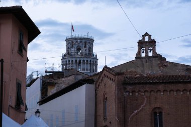 Akşam Pisa 'da bir sokakta. Eğik Pisa Kulesi arka plandaki binaların arkasından dışarı bakıyor. Akşamları eski İtalyan şehri Pisa.