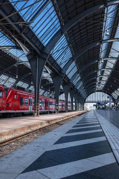 Karlsruhe, Almanya - 20.05.2025: Bir Alman şehrindeki büyük tren istasyonu. Almanya 'da bir tren istasyonunun platformunda kırmızı bir tren duruyor. Metal kolonlar ve çatı kemerleri.