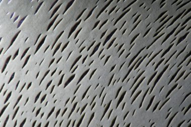 Düzensiz uzatılmış girintili gri desenli bir yüzeye yakın plan. Şekillerin rastgele düzenlenmesi dinamik ve ilgi çekici bir model yaratır..