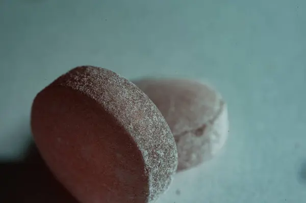 İki kırmızı kiraz aromalı şekerin yakın çekimi, kristalize, desenli bir yüzeyi var. Parlak renkleri ve şekerli kaplamaları onları çekici kılıyor. Lezzetli meyveli tatlarını yansıtıyor..