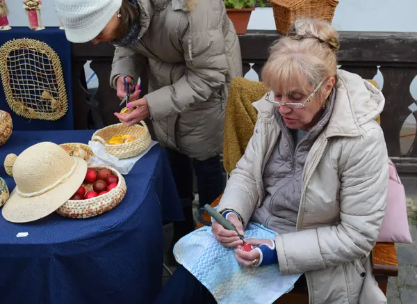 Hollk Paskalya Festivali - Hollk, Macaristan - 18 Nisan 2022 - Geleneksel Macar Paskalya Festivali 'nde Paskalya Yumurtası İşleyen Yaşlı Kadın. Paskalya el işi fuarı, asırlık bir gelenek..