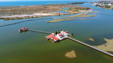 Agios Nikolaos 'un Kutsal Manastırı büyük bir lagünün kalbinde huzur içinde uzanır. Resmedilmeye değer ahşap bir köprüyle toprağa bağlanır..