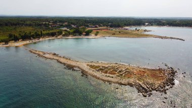 Hava Aracı Manzarası, antik harabeleri ve turkuaz denizi olan yarımada kıyısı. Temiz mavi sular, sahil boyunca kayalık kalıntılar. Akdeniz kıyısı, manzaralı yaz manzarası.