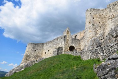 Orta Avrupa 'nın en büyük ortaçağ kaleleri olan Spis Kalesi' nin kalıntıları Slovak dağlıklarında yeşil bir tepenin üzerinde yer alıyor. Taş duvarlar ve siperler zengin tarihi, mimariyi ve mirası yansıtıyor. Yeşil çimenler ve bulutlu yaz gökyüzü. 