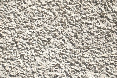 Gömülü küçük taşların oluşturduğu kaba, desenli bir yüzeye sahip pürüzlü ya da çakıl taşı çizgili bir duvar. Sert, açık gri dış kaplama, çimento, sıva ve kaplama gibi doğal duvar malzemeleri. Mimari, inşaat, ya da cephe tasarımı, arkaplan, 