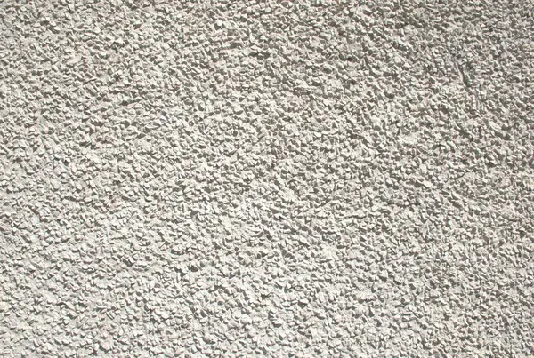Gömülü küçük taşların oluşturduğu kaba, desenli bir yüzeye sahip pürüzlü ya da çakıl taşı çizgili bir duvar. Sert, açık gri dış kaplama, çimento, sıva ve kaplama gibi doğal duvar malzemeleri. Mimari, inşaat, ya da cephe tasarımı, arkaplan, 