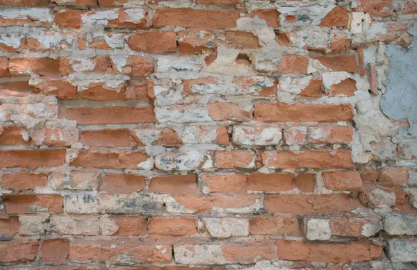 Kırmızı ve beyaz yıpranmış tuğlaları ve açıkta bırakılmış harcı olan eski bir tuğla duvarın yakın çekimi. Kırsal, yontulmuş yüzey yaş ve çürüme belirtileri gösteriyor, bu da onu dokulu bir arka plan ya da mimari detay olarak kullanılmak için ideal kılıyor, duvar kağıdı. 