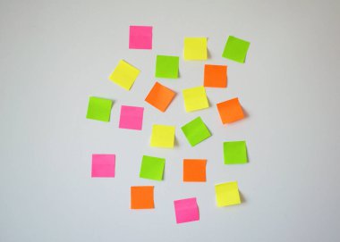 Rastgele yerleştirilmiş pembe, sarı, yeşil ve turuncu notlar beyaz bir duvara saçılmış planlama, beyin fırtınası, hatırlatıcı ve verimliliği sembolize ediyor. Ofis için ideal, eğitim için, yaratıcı wo