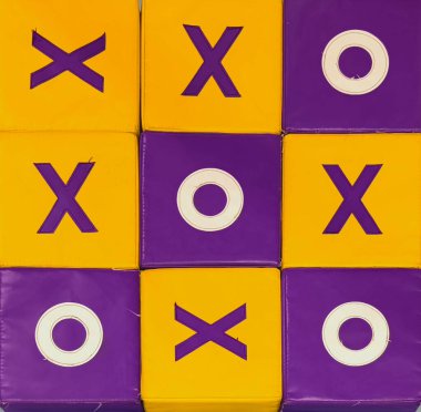 Sarı ve mor renkli yumuşak bloklardan oluşan canlı bir Tic Tac Toe oyun tahtası, kabartmalı X ve O sembolleri oyuncu bir desen içeriyor