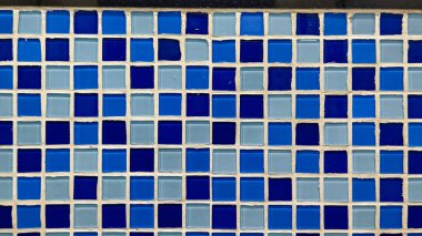 Parlak mozaik duvarda mavi ve açık mavi fayanslar düz geometrik şablon şeklinde dizilmiş.