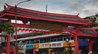 Canlı kırmızı bir Çin kapısı Bogors Suryakancana Caddesi 'nde fenerlerle süslenmiş, yerel dükkanlar ve tabelalarla çevrili.