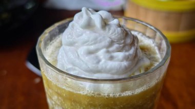Üstünde krema olan lezzetli bir soğuk içecek. Temiz bir bardakta servis ediliyor. Tazelik yayıyor.