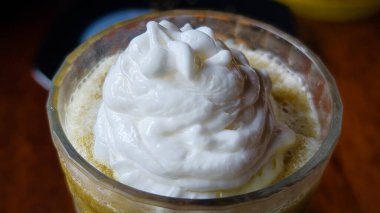 Üstünde krema olan lezzetli bir soğuk içecek. Temiz bir bardakta servis ediliyor. Tazelik yayıyor.