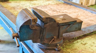 Kesme, delme ya da montaj sırasında nesneleri sıkıca tutmak için kullanılan eski bir mavi metal mengenenin yakın çekimi.