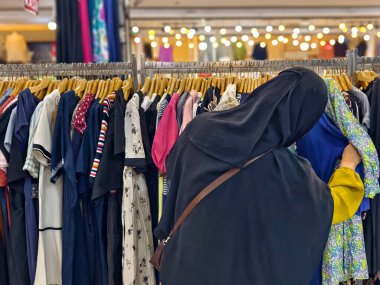 Bogor, Endonezya - 11 Mayıs 2025: Elbiseler ve gömlekler de dahil olmak üzere çeşitli kıyafetler, iyi aydınlatılmış geleneksel bir pazarda raflarda sergilendi. Yüksek kalite fotoğraf